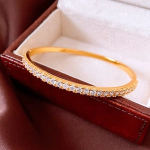 Close-up of 24K gold plated bangle with sparkling crystals on a silk background
