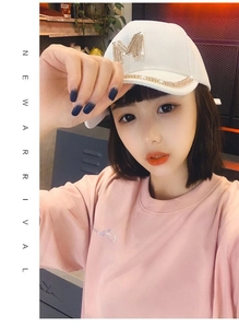 Close-up of white baseball cap with rhinestone M logo worn by model in casual setting