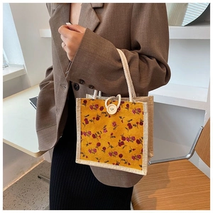 Detail of vintage floral handbag in yellow with cord handles and a white button closure