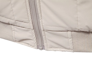 Detailed macro view of beige jacket zipper, stitching quality and ribbed hem finish