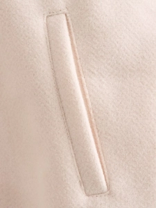 Macro shot of reinforced stitching on the pocket of a beige wool-like casual jacket