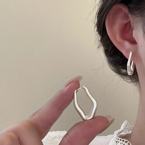 Close-up of silver irregular geometric hoop earrings with a unique twisted metal design