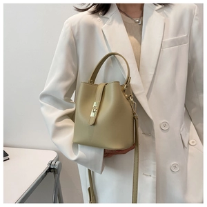 Detail of beige bucket bag showing gold hardware accents and texture of the PU leather