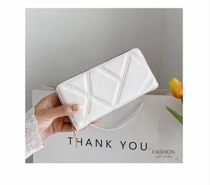 Elegant white quilted long wallet with gold zipper held by a hand near tulips
