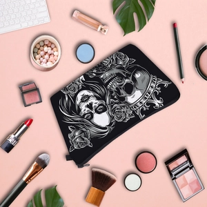Flat lay of skull patterned makeup bag with cosmetics on a pink background
