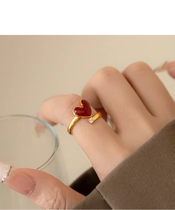 Close-up of 18k gold heart ring with red enamel and zircon on a hand