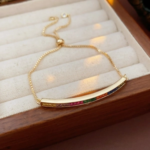 Close-up of golden box chain bracelet with rainbow gradient zircon stones on a jewelry box