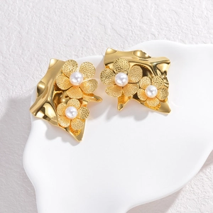Elegant gold flower tassel earrings with white pearls on a minimalist white stone display
