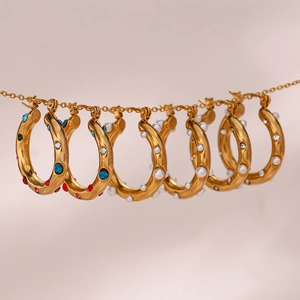 Detailed macro of gold hoop earrings with colorful cubic zirconia and faux pearls