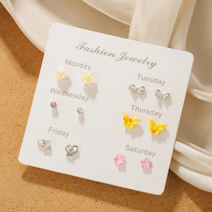 Detailed set of six pairs of butterfly and floral stud earrings on a white weekday card