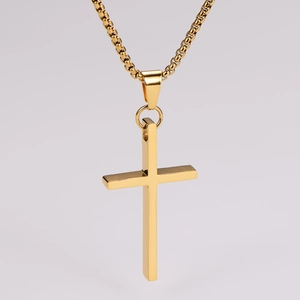 Close-up of polished gold cross pendant with a delicate box chain on grey background