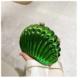 Close-up of metallic green shell clutch with pleated texture and golden ball clasp