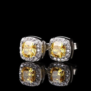 Macro detail of silver halo earrings featuring yellow cushion-cut stones on black background