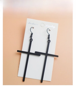 Detail view of punk style black matte cross earrings hanging on a white jewelry card