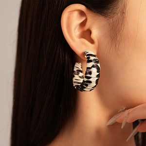 Gros plan sur une grande boucle d'oreille en C avec un motif zébré noir et blanc chic
