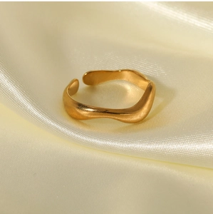 Macro detail of golden wave shaped stainless steel ring on elegant satin background