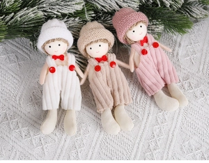 Close-up of three knitted Christmas doll ornaments in white, khaki and pink outfits