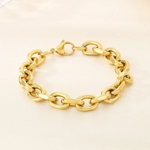 Close-up of golden chunky chain bracelet with lobster clasp on beige silk background