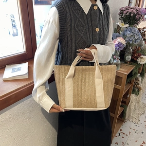 Detail of beige straw woven tote bag with off-white canvas handles in natural cafe light