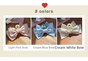 Close-up of oversized satin bow hair claws in light pink, creamy blue, and white colors