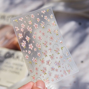 3D embossed cherry blossom nail stickers with golden edges held by a hand