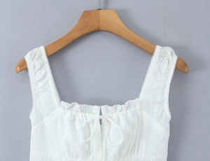 Detail of white lace dress featuring delicate embroidery and drawstring bow decoration