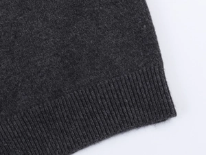 Close-up of dark grey knit cardigan showing fine wool texture and ribbed cuff detail