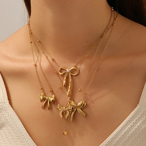 Collier multi-rangs doré à nœuds avec perle et pendentif cœur sur mannequin