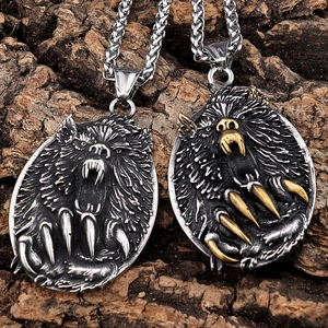 Detail of silver and gold-tone roaring wolf head pendants on textured tree bark background