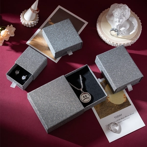 Macro shot of silver glitter jewelry gift boxes with silk pull tabs on red fabric