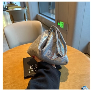 Détail d'un sac à main à paillettes argentées sur une table en bois dans un salon moderne