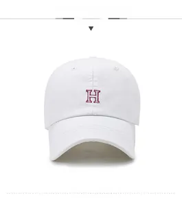 Détail de la casquette en coton blanc avec lettre H brodée rose et visière courbée