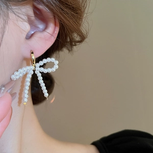 Gros plan détaillé d'une boucle d'oreille nœud en perles avec anneau doré pour femme