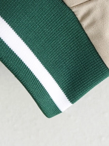 Detail of green ribbed cuffs with white stripes on a beige twill fabric baseball jacket