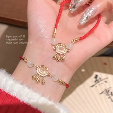 Detail of red woven bracelet with golden Ruyi lock pendant and white jade stone
