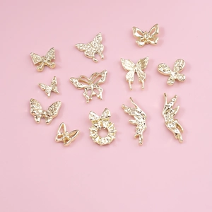 12-piece gold alloy nail art set with hollow butterfly and bow charms on pink background