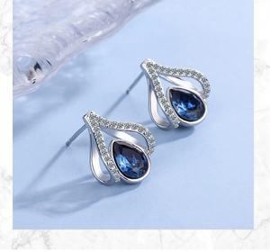 Macro detail of silver drop earrings with blue crystal and white cubic zirconia