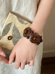 Close-up of bohemian coconut shell and wood bead stretch bracelet worn by a model