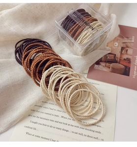 Close-up of elastic hair bands in earthy tones with striped texture in a clear acrylic box