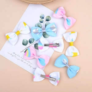 Détail de barrettes à nœuds colorés avec motifs arc-en-ciel et étoiles pour enfants