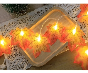 Close-up of LED maple leaf string lights with warm white glow on a rustic wooden tray