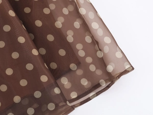 Detailed close-up of brown organza fabric with beige polka dots and sheer texture