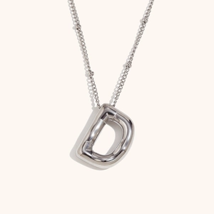 Macro shot of silver 18K stainless steel 3D puffy initial D pendant and chain necklace