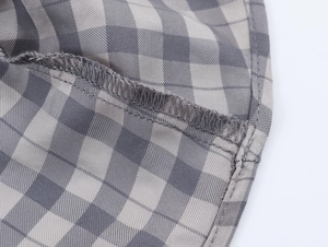 Gros plan du tissu à carreaux gris et beige montrant les coutures de qualité d'une robe