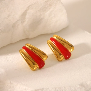 Detailed view of 18k gold plated earrings with red enamel on a stone surface
