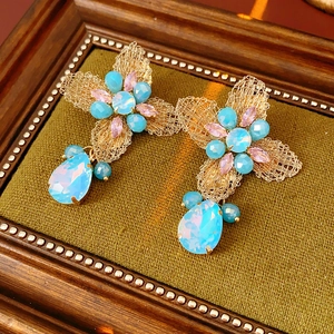 Detailed macro view of vintage flower earrings with pink and blue gemstones on wood