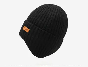 Gedetailleerd zijaanzicht van een dikke zwarte gebreide muts met een oranje patch