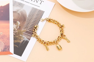 Close-up of double-layer gold chain bracelet with heart padlock and key charms