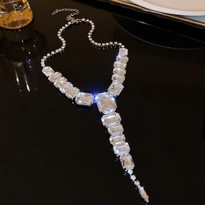 Macro detail of geometric crystal pendant necklace with emerald-cut zirconia on dark mirror