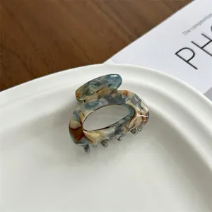 Elegant tortoiseshell acetate hair claw clip with vintage marble pattern on a white plate